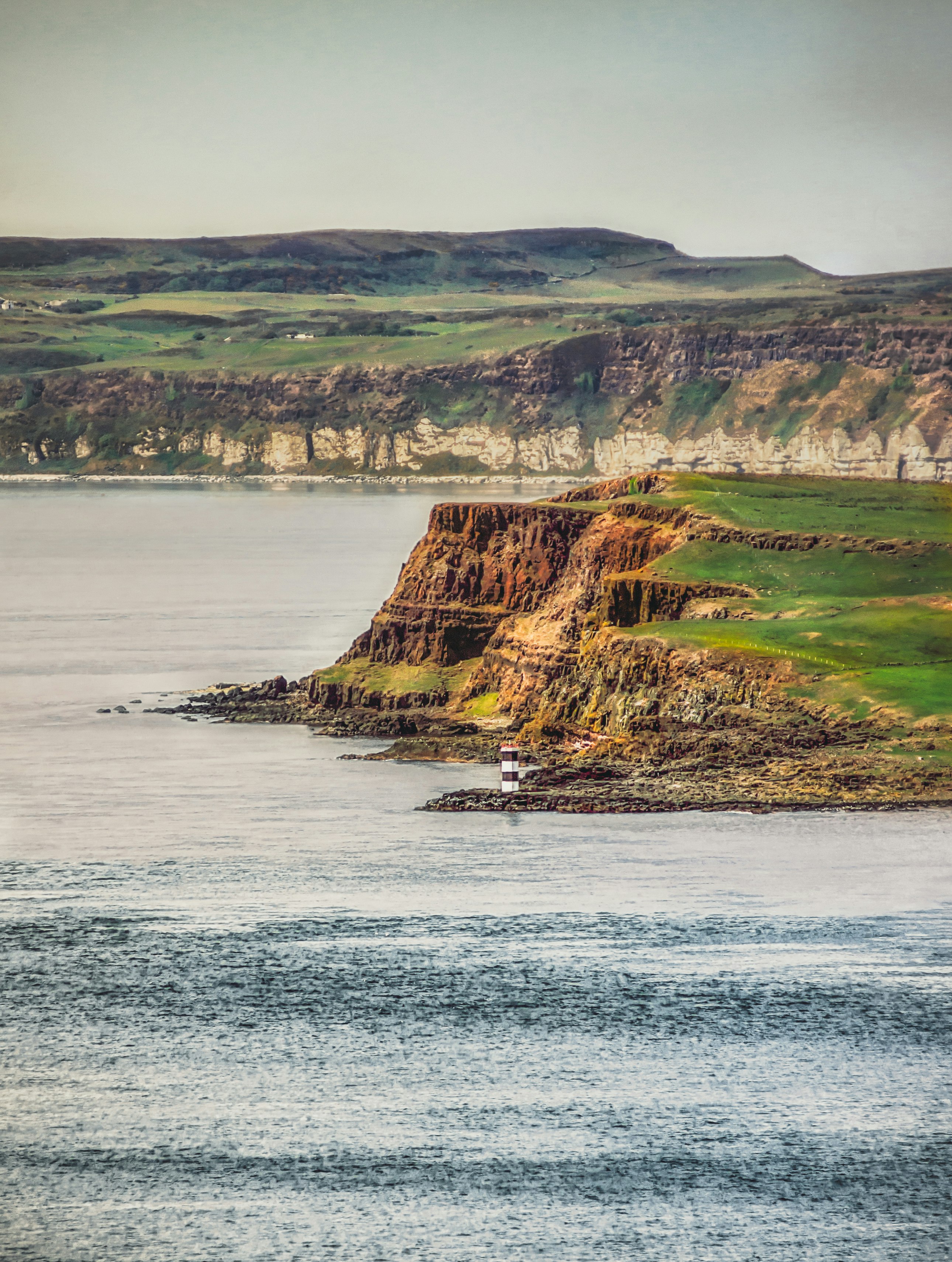 green and brown mountain beside body of water during daytime